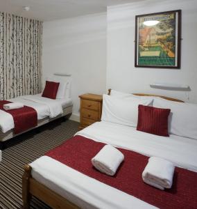 a hotel room with two beds with red and white sheets at St Athans Hotel in London