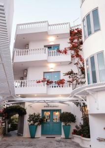 ein weißes Gebäude mit grüner Tür und roten Blumen in der Unterkunft Harmony Hotel in Sarandë