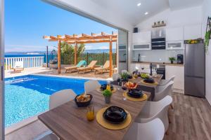 cocina y sala de estar con mesa de comedor y piscina en Villa Matan - only 200m from the sandy beaches, private 28m2 pool, en Omiš