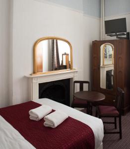 - une chambre avec un lit, un miroir et une chaise dans l'établissement St Athans Hotel, à Londres