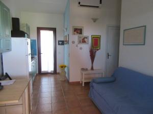 un soggiorno con divano blu e una cucina di Villetta Sunrise 6A a Costa Rei