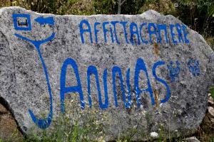 un panneau sur un rocher avec une inscription bleue sur celui-ci dans l'établissement Affittcamere Jannas, à Orgosolo