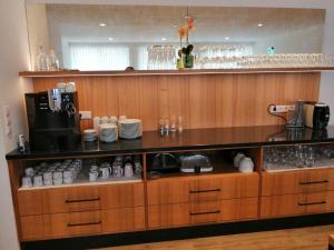 a kitchen with wooden cabinets and a counter with cups at Landhotel Reckenberg in Stegen