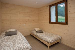 two beds in a wooden room with a window at gîtes à la ferme dela le var in Guillaumes