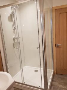 W łazience znajduje się prysznic ze szklanymi drzwiami. w obiekcie Pleasant Point Holiday Cottages w mieście Rosemarkie