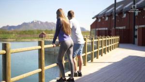 a man and a woman standing next to a fence at Lofoten rorbuutleie - Lilleeidet in Gravdal