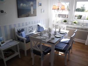 a dining room with a table and chairs and windows at Ferienwohnung Seestern - Alte Schmiede Neugarmssiel in Wangerland