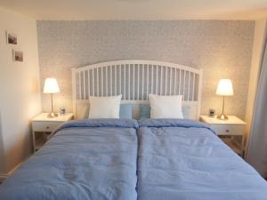 1 dormitorio con 1 cama con sábanas azules y 2 lámparas en Ferienwohnung Seestern, en Wangerland