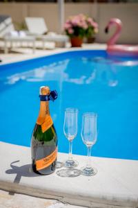 una bottiglia di champagne e due bicchieri accanto alla piscina di Villa Branka apartments near Dubrovnik with Pool a Ivanica