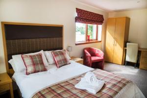 um quarto de hotel com uma cama e uma cadeira vermelha em Ardennan House Hotel em Inverurie
