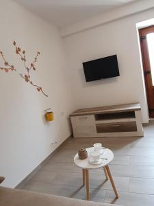 a white living room with a table and a tv at Apartman Mi in Nerezine