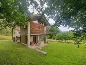 un bâtiment dans un champ d'herbe avec un arbre dans l'établissement La casa del Ghiro - PARCO DOLOMITI BELLUNESI, à Corazzai