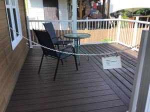 une terrasse couverte avec 2 chaises et une table. dans l'établissement Petit Hôtel Amara, à La Malbaie
