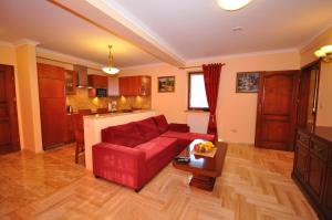 a living room with a red couch and a kitchen at Apartament Plumeria in Zakopane