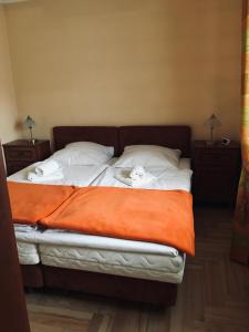 a bed with two pillows and an orange blanket at Apartament Plumeria in Zakopane