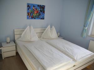 a white bed with white sheets and pillows at Sünnenkringel 68 Appartement 1 in Zingst