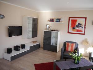 ein Wohnzimmer mit einem TV und einem Stuhl in der Unterkunft Sünnenkringel 68 Appartement 1 in Zingst