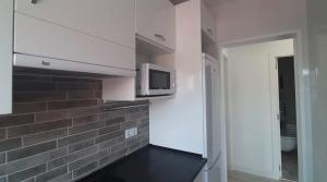 een keuken met een magnetron en een bakstenen muur bij White Apartment in Lloret de Mar