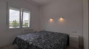 een slaapkamer met een bed en een raam bij White Apartment in Lloret de Mar