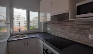 een keuken met een wastafel en een magnetron bij White Apartment in Lloret de Mar