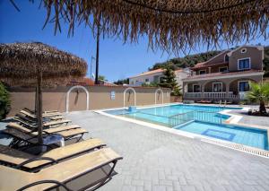 a swimming pool with lounge chairs and an umbrella at Maria Apartments in Sidari