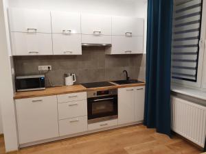 a kitchen with white cabinets and a sink and a microwave at Apartament Aga in Ustrzyki Dolne
