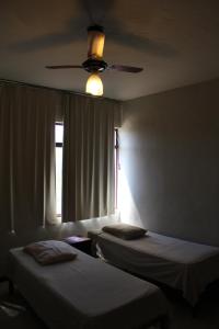 a room with two beds and a ceiling fan at Hotel Aquarius in Coronel Fabriciano