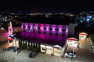 a purple building with cars parked outside at night at Hotel Polaris in Suceava