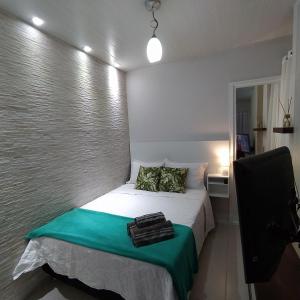 um pequeno quarto com uma cama com um cobertor verde em Loft encantador B - 8 km de Floripa em São José