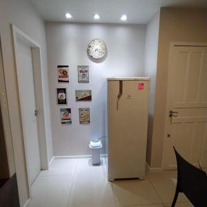 a room with a refrigerator and a clock on the wall at Loft encantador B - 8 km de Floripa in São José