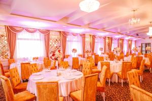 una sala de banquetes con mesas y sillas blancas y una lámpara de araña en Hotel Polaris, en Suceava