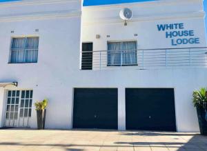 ein weißes Haus mit zwei Garagentüren davor in der Unterkunft White House lodge in Mthatha