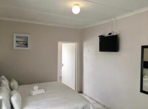 a bedroom with a white bed and a television at White House lodge in Mthatha +4 photos