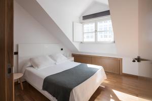 1 dormitorio con cama blanca y ventana en Atico en Santa Catalina, en A Coruña