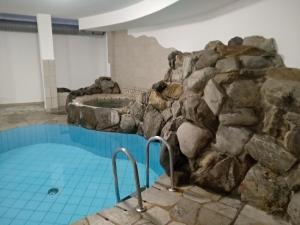 a swimming pool with a stone wall and a tub at Hotel Rainhof in Senales