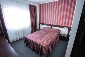 a bedroom with a bed with a pink blanket at Hotel Polaris in Suceava