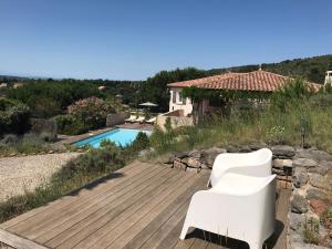 Caunes-MinervoisにあるCozy Villa in Caunes Minervois with Swimming Poolの木製デッキ(白い椅子、スイミングプール付)