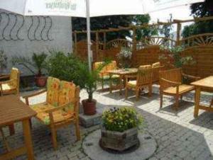 eine Terrasse mit Tischen, Stühlen und einem Sonnenschirm in der Unterkunft Hotel Kastanienhof in Threna