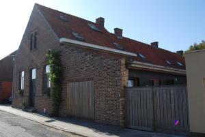 una casa de ladrillo con una puerta y una valla en Het Oud Schoolmeesterhuis en Watou