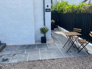 un patio con mesa y sillas junto a un edificio en Greenbank, Lower Greenbank Guest Suite, en Oban