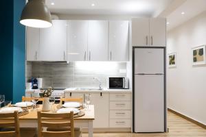 a kitchen with a table and a white refrigerator at Luxury Seaview Apartment Con Vista in Loutraki