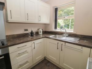 a kitchen with white cabinets and a sink and a window at Acorn Cottage in Morpeth