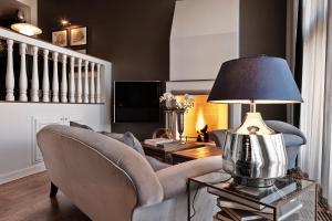 a living room with a couch and a lamp on a table at Nimb Hotel in Copenhagen