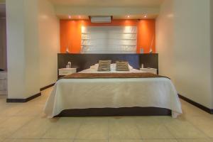 a bedroom with a large bed with an orange wall at Hotel La Laguna Galapagos in Puerto Villamil