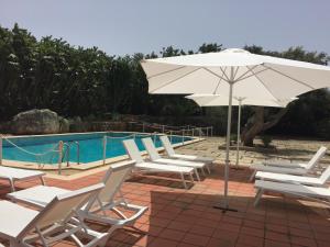 a group of chairs and an umbrella next to a pool at Resort Villa Isola B&B in Syracuse