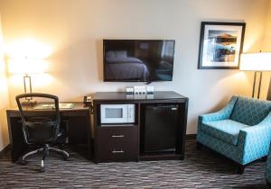 Habitación de hotel con escritorio, TV y silla en Cottage Grove Inn, en Cottage Grove