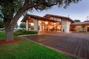 an exterior view of a building with a tree at Inn of the Hills Hotel and Conference Center in Kerrville