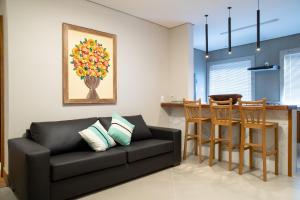 a living room with a black couch and a kitchen at ESPAÇO 250 - Apto mobiliado, 3 quartos, sendo uma suíte, banheiro social, cozinha completa, sala de estar, ar condicionado, tv e internet in Tiradentes
