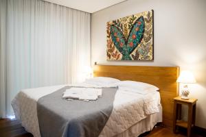 a bedroom with a large bed with two towels on it at ESPAÇO 250 - Apto mobiliado, 3 quartos, sendo uma suíte, banheiro social, cozinha completa, sala de estar, ar condicionado, tv e internet in Tiradentes