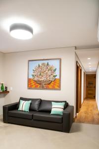 un sofá negro en una sala de estar con una pintura en la pared en ESPAÇO 250 - Apto mobiliado, 3 quartos, sendo uma suíte, banheiro social, cozinha completa, sala de estar, ar condicionado, tv e internet, en Tiradentes